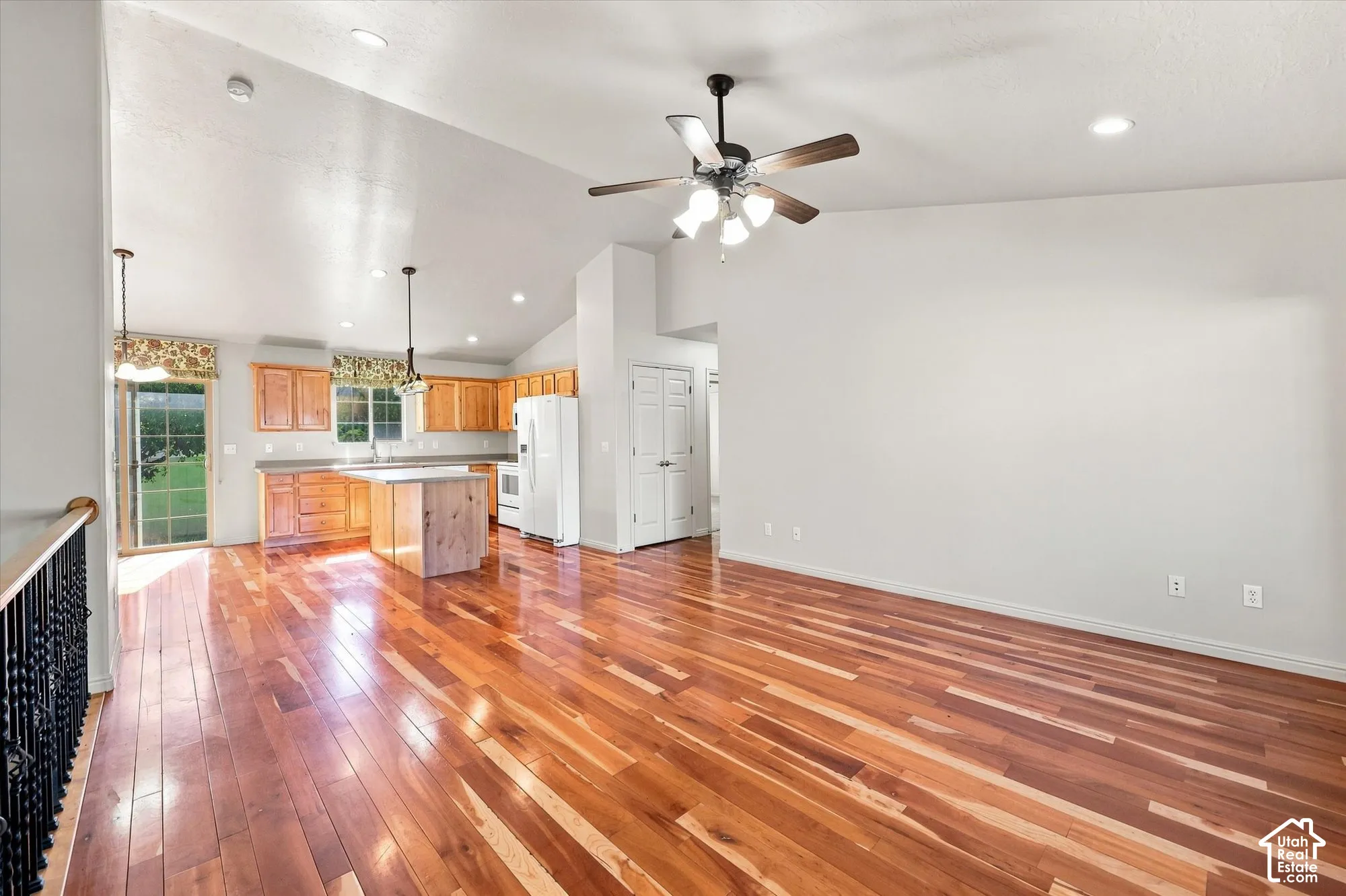 Hardwood flooring, vaulted ceiling, recessed lighting, kitchen island, and a sliding glass door
