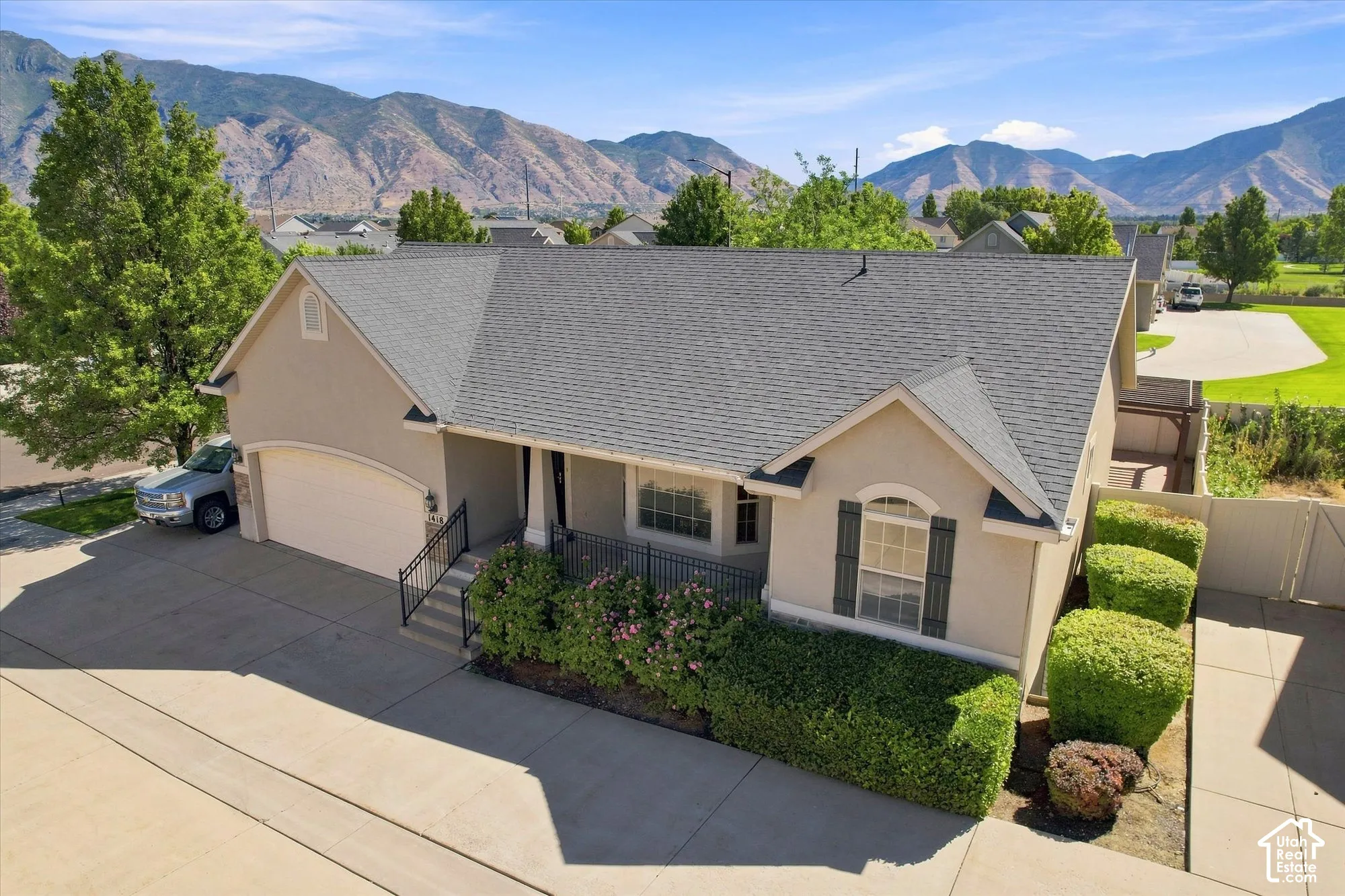 Stucco exterior with a shingled roof, arched garage door, and decorative window shutters