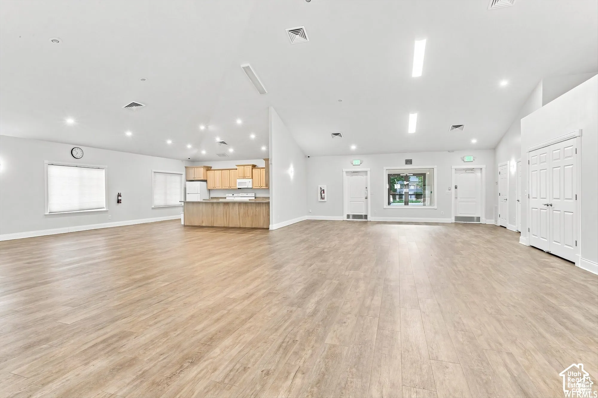 Spacious open-concept room featuring wood-finish flooring, recessed lighting, and ample natural light from multiple windows
