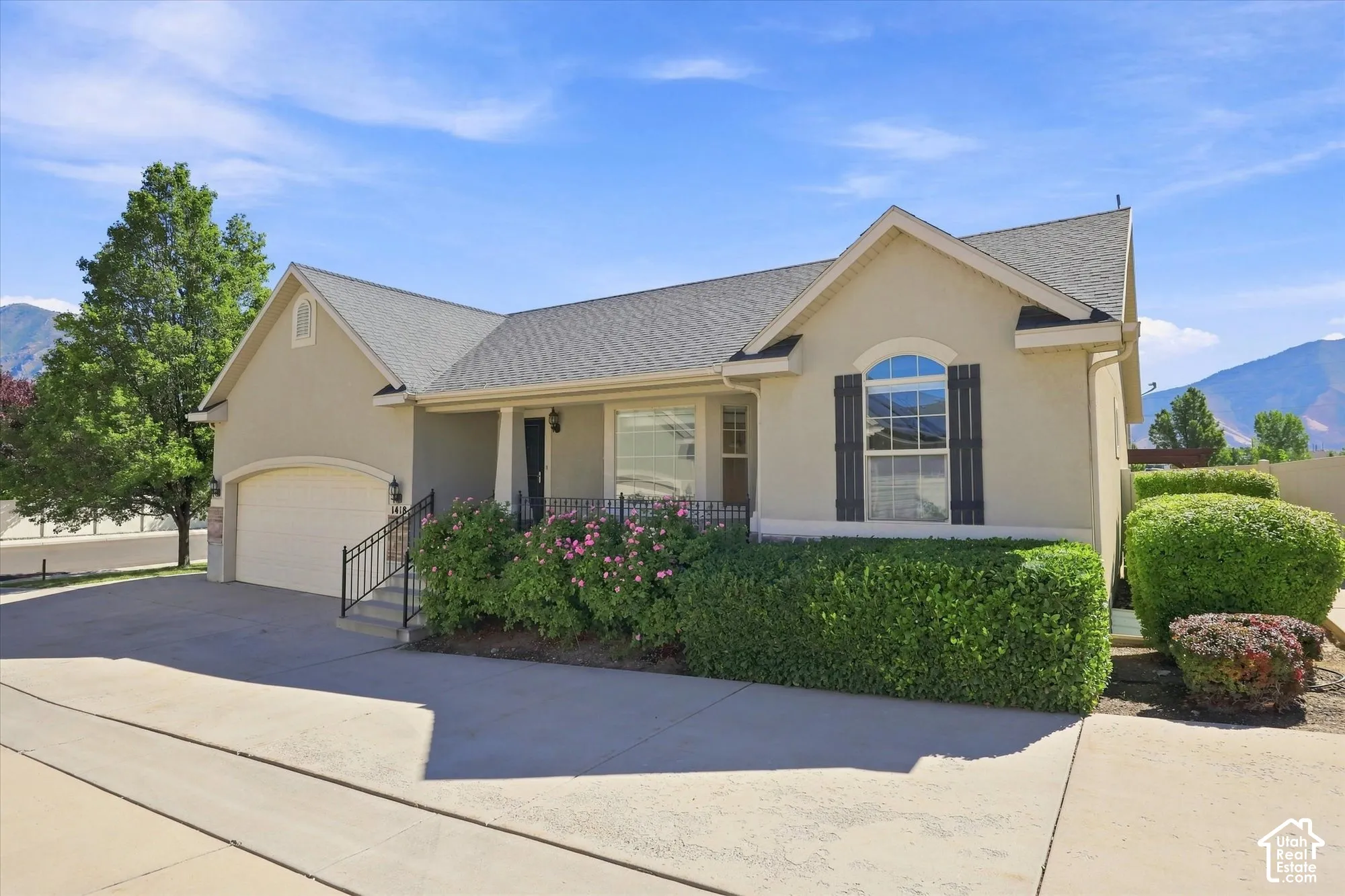Stucco exterior with a gabled roofline, arched window with shutters, and an attached garage