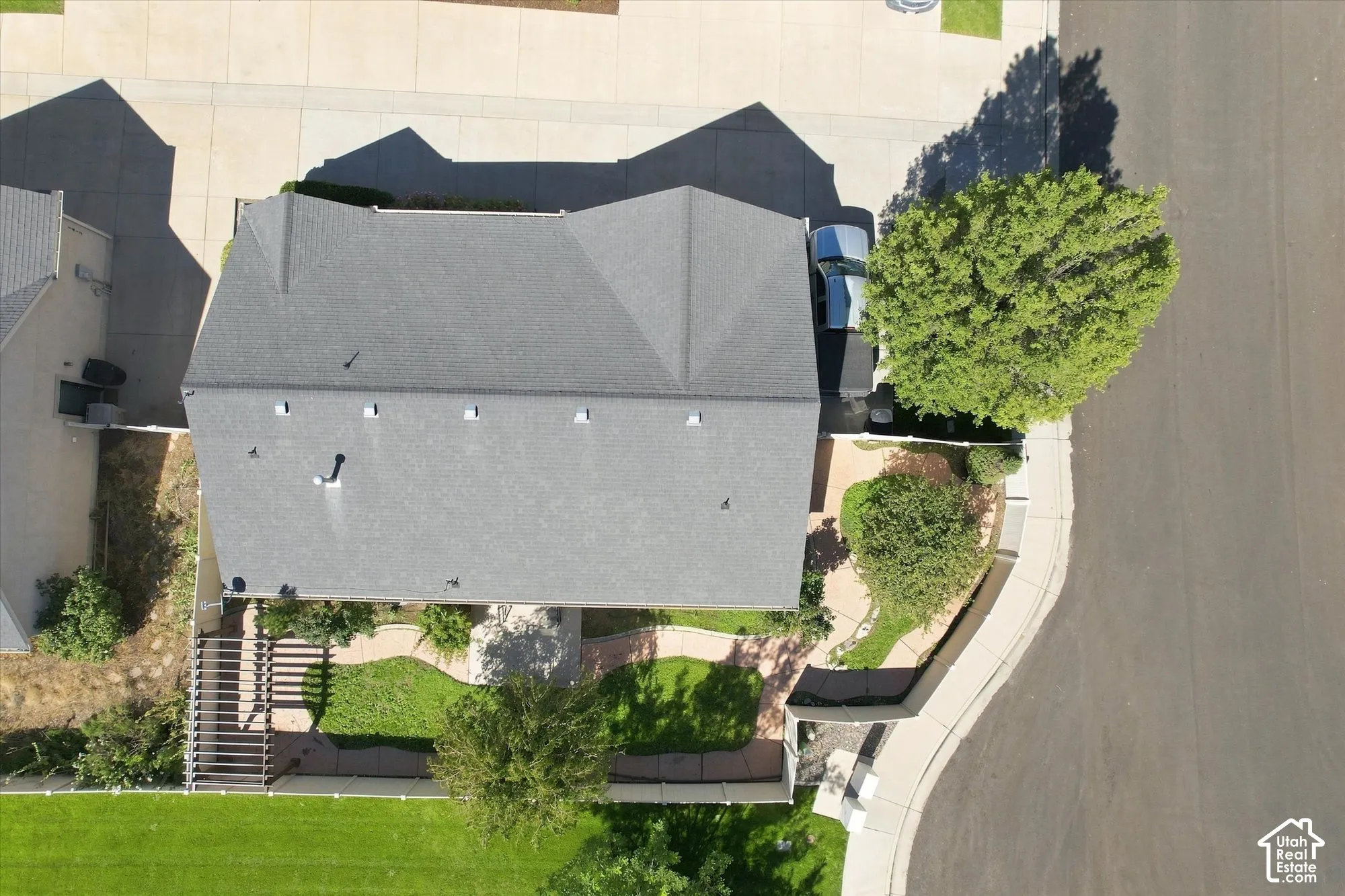 Gabled roofline, concrete driveway, front yard landscaping, mature trees, and street-facing curb appeal