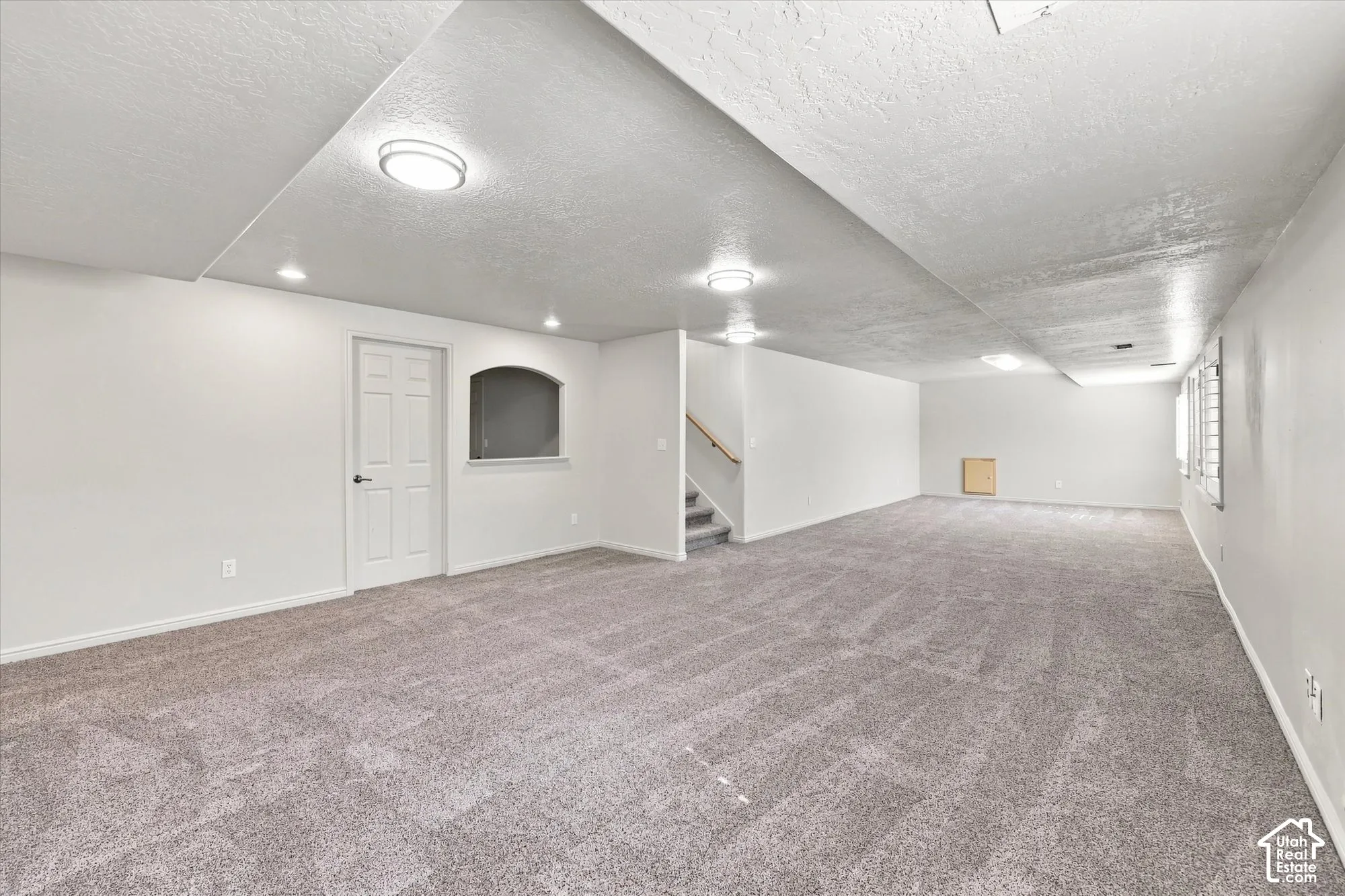 Expansive carpeted area with neutral wall finishes and recessed lighting