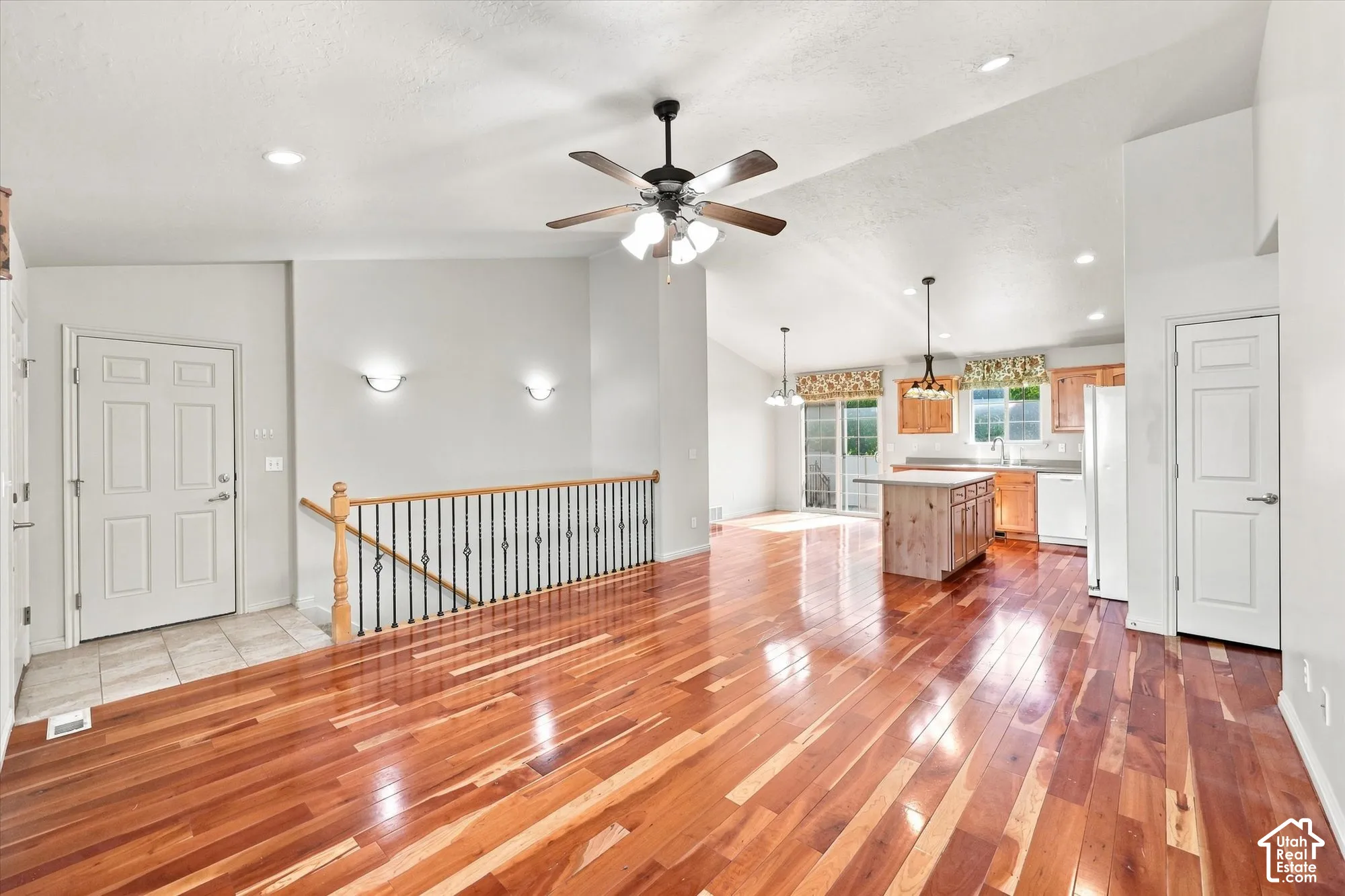Wood-finish flooring throughout, vaulted ceiling, recessed lighting, ceiling fan with integrated lighting, and an open-concept kitchen with a central island