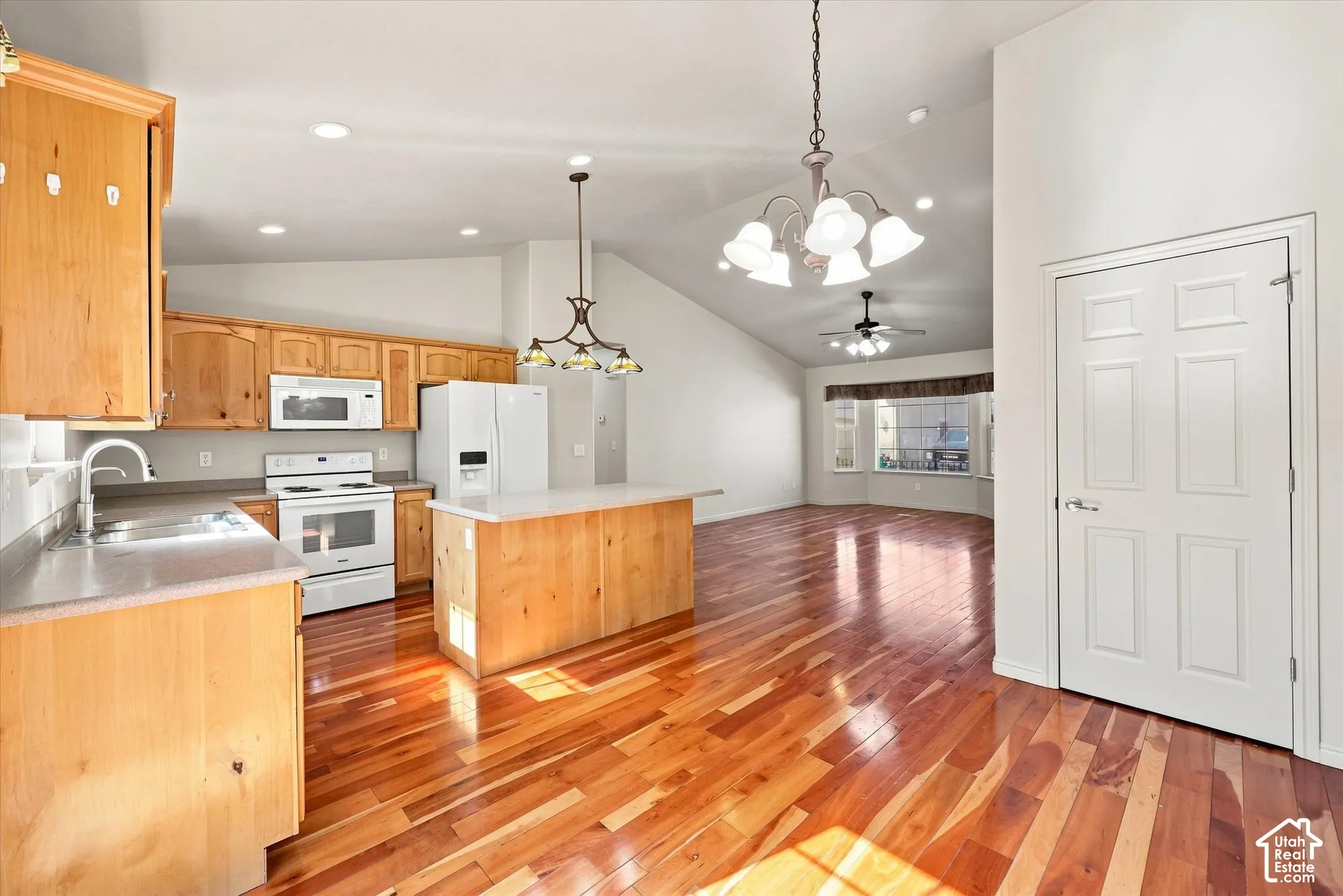 Kitchen featuring wood cabinetry, white appliances, a center island with a light-colored countertop, and recessed lighting