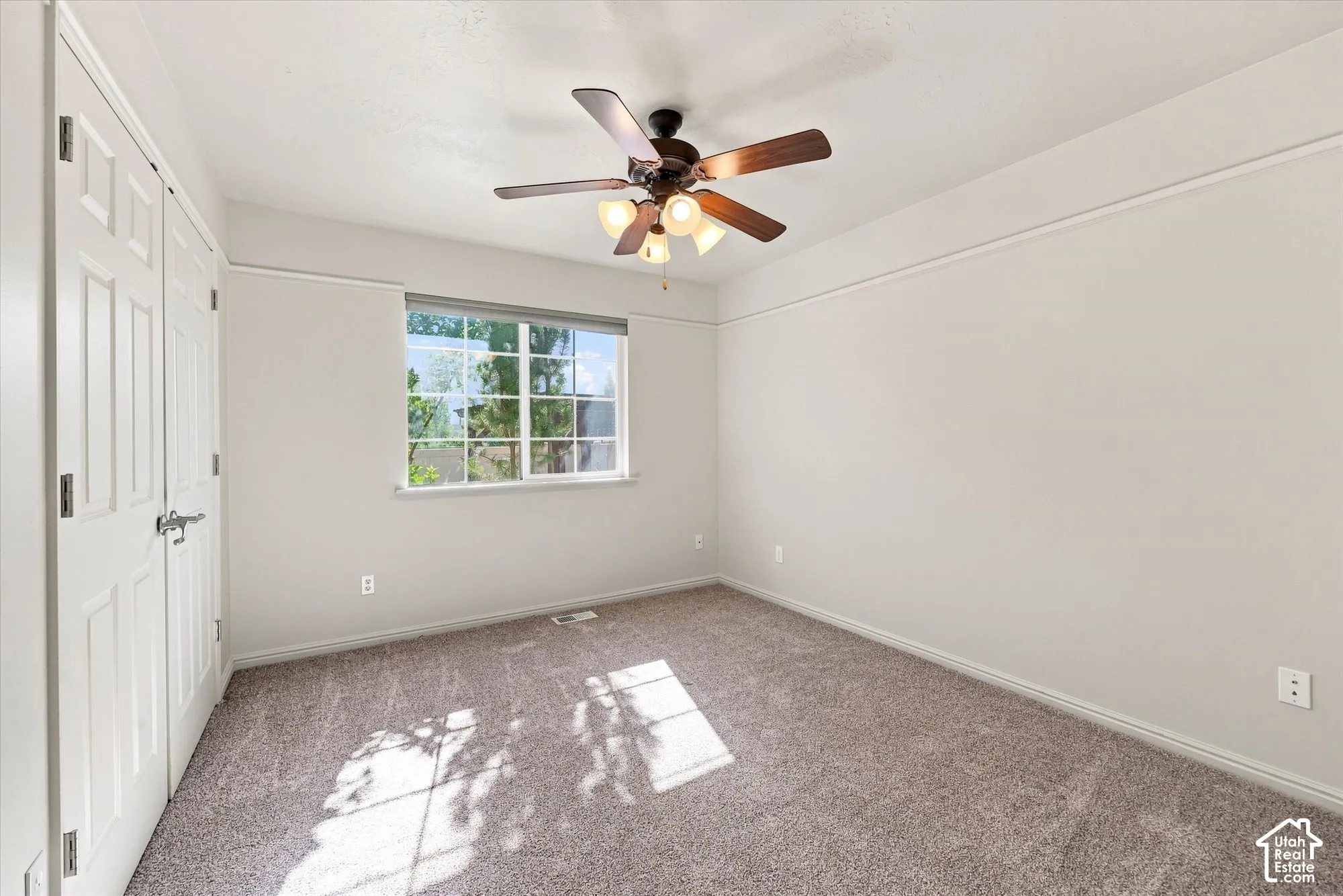 Neutral-toned wall paint, textured carpeting, contemporary ceiling fan with lighting, white trim work, and a window with natural light