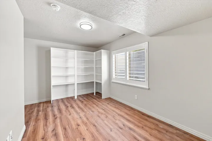 Built-in shelving, wood-finish flooring, recessed lighting, and a window with plantation shutters