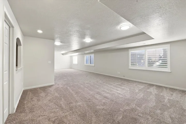 Spacious room featuring neutral carpeting and multiple windows with plantation shutters