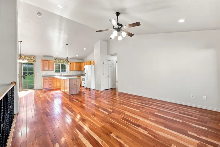 Hardwood flooring, vaulted ceiling, recessed lighting, kitchen island, and a sliding glass door
