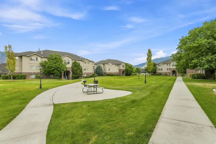 Expansive green space featuring paved walkways, mature trees, and exterior lighting fixtures