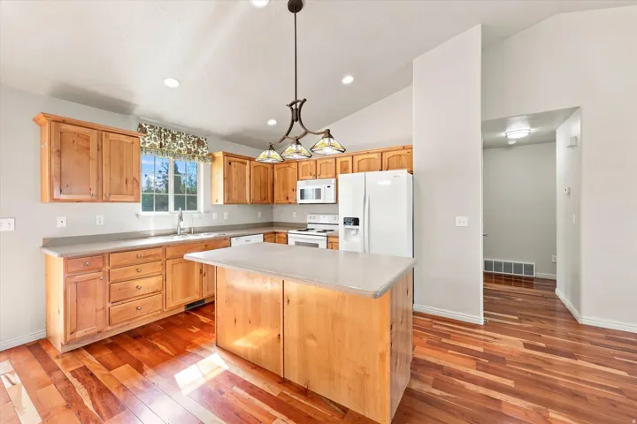 Spacious kitchen featuring abundant wood cabinetry, an island with countertop, and wood-finish flooring