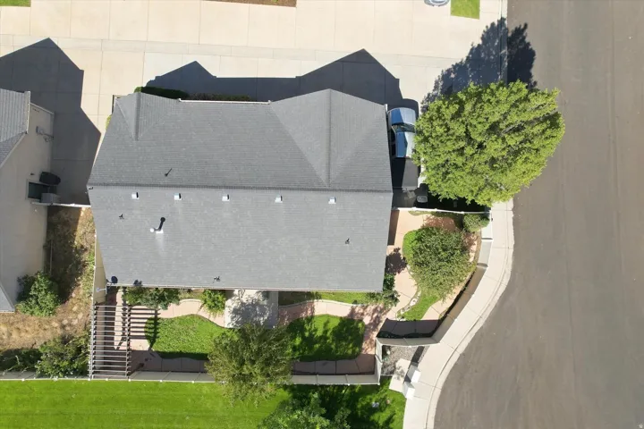 Gabled roofline, concrete driveway, front yard landscaping, mature trees, and street-facing curb appeal