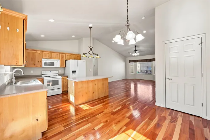 Kitchen featuring wood cabinetry, white appliances, a center island with a light-colored countertop, and recessed lighting