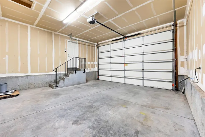 Concrete flooring with a white sectional garage door and automatic opener