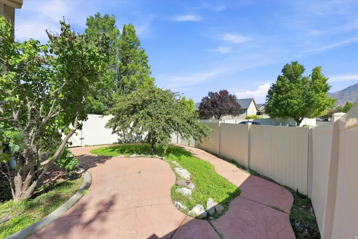 Stained concrete walkway, established trees, privacy fencing, and landscaping elements