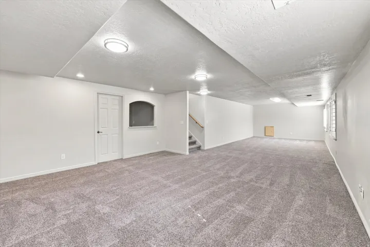 Expansive carpeted area with neutral wall finishes and recessed lighting