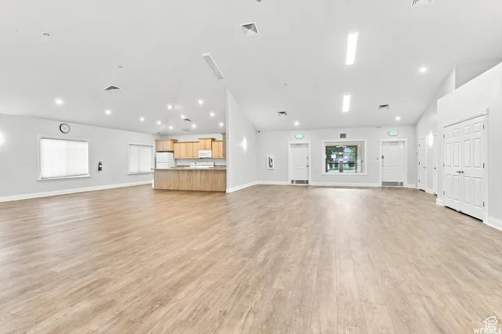 Spacious open-concept room featuring wood-finish flooring, recessed lighting, and ample natural light from multiple windows