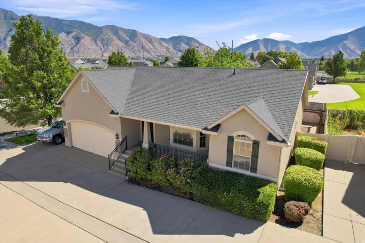 Stucco exterior with a shingled roof, arched garage door, and decorative window shutters