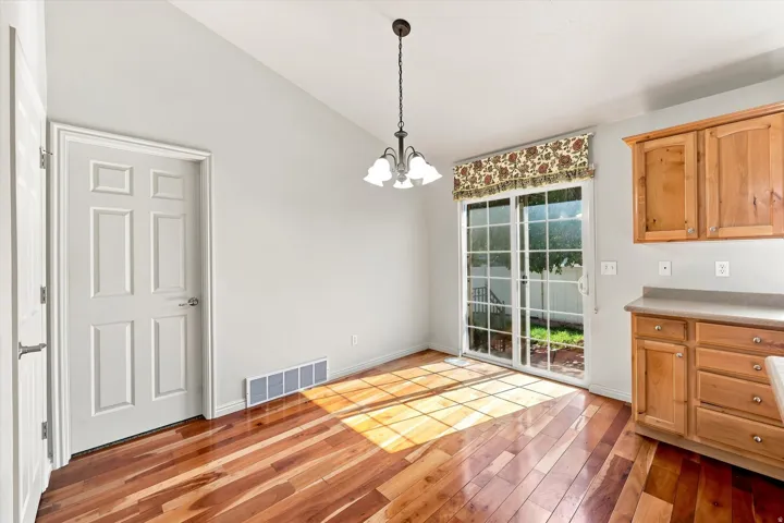 Wood-finish flooring, sliding glass door, overhead lighting fixture, wood cabinetry, and neutral countertops