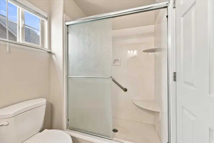 Shower enclosure with frosted glass panels, built-in seating, and a grab bar