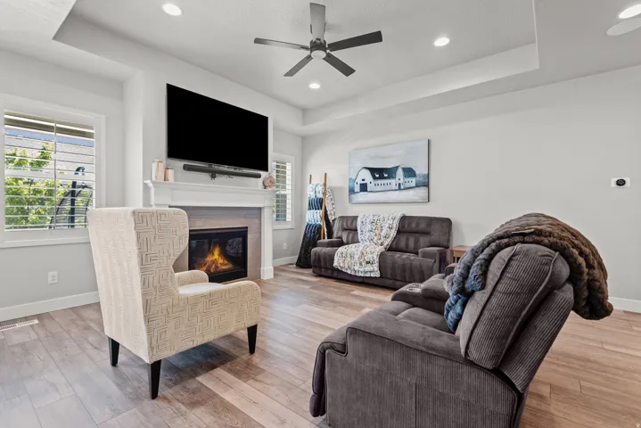 Living area featuring wood-finish flooring, a tray ceiling, and a ceiling fan