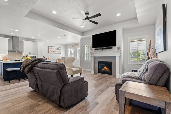 Open-concept living space featuring comfortable seating arrangements, wood-finish flooring throughout, and a fireplace with electric insert