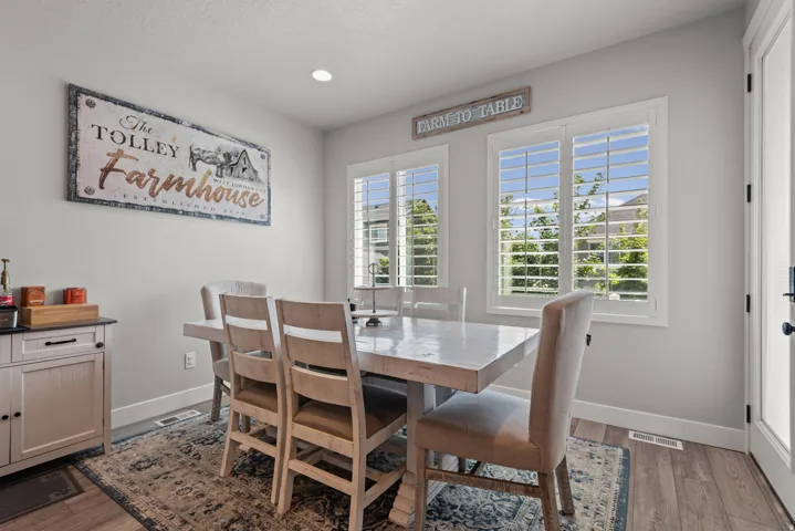 Dining area featuring two windows with white plantation shutters, wood-finish flooring, and a recessed ceiling light