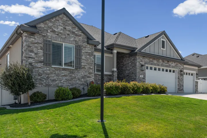 Contemporary exterior with stone facade, dark gray siding accents, and a two-car garage