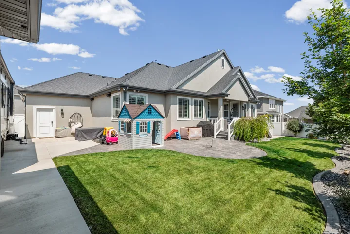 Expansive backyard featuring a manicured lawn, a large stamped concrete patio, and a privacy fence