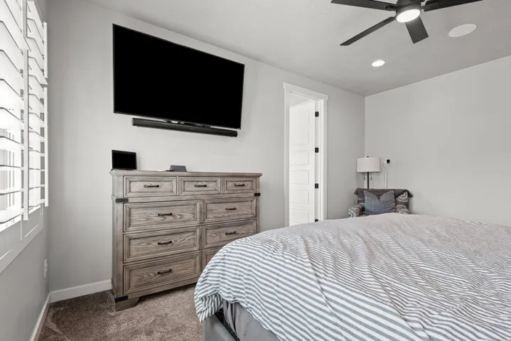 Bedroom featuring white plantation shutters, a ceiling fan with integrated lighting, and recessed ceiling lighting