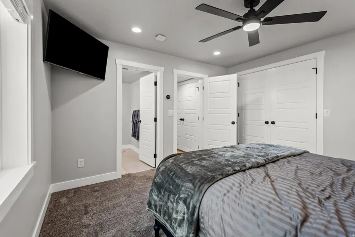 Carpeted interior space featuring a matte black ceiling fan with integrated lighting, recessed ceiling lights, and white trim molding