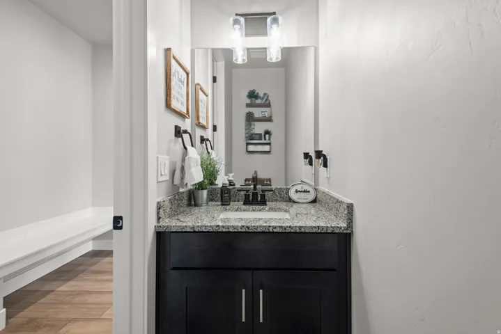 Bathroom vanity featuring a granite countertop, undermount sink, and black wood-finish cabinetry