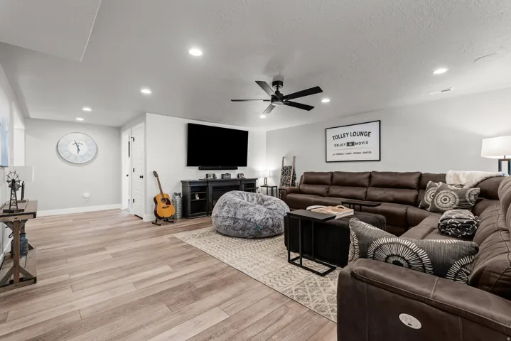 Spacious entertainment area featuring wood-finish flooring, recessed lighting, and a ceiling fan