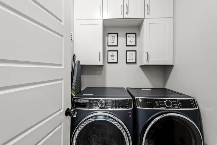 Dedicated laundry area featuring white shaker-style cabinetry with chrome hardware