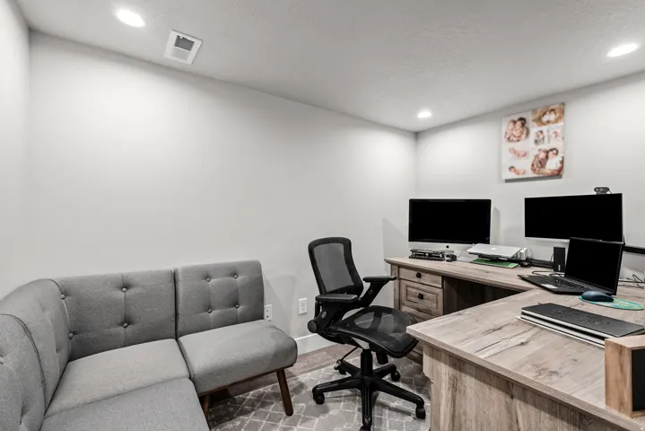 Spacious room featuring light gray walls, recessed lighting, and a durable L-shaped wood-finish desk