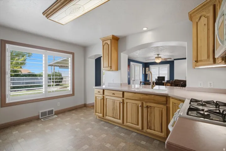 Spacious kitchen featuring custom wood cabinetry, stainless steel gas cooktop, and a large center island with wood-finish countertops