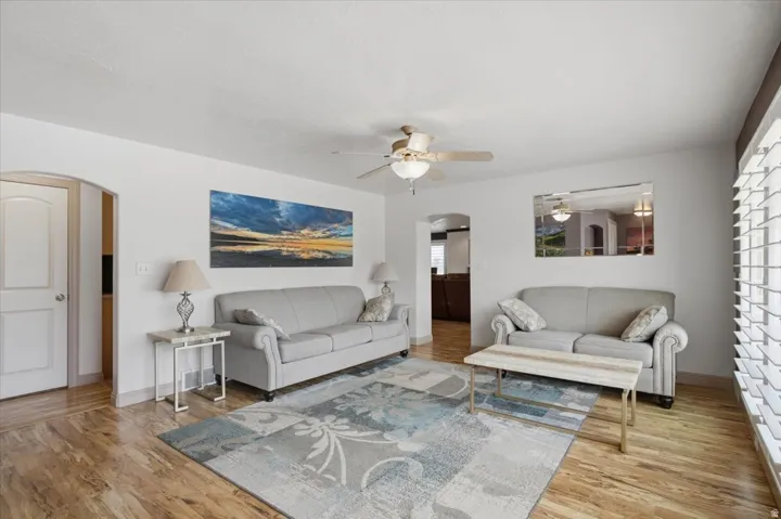 Bright and spacious living area showcasing hardwood flooring, neutral wall finishes, and abundant natural light from multiple windows