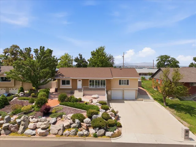 Split-level residence featuring a two-car garage, concrete driveway, and a terraced front yard with rock landscaping