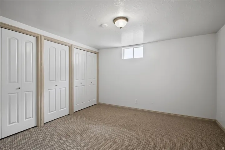 Recessed window providing natural light, warm neutral wall tones, textured ceiling, flush mount ceiling fixture, and patterned carpet flooring
