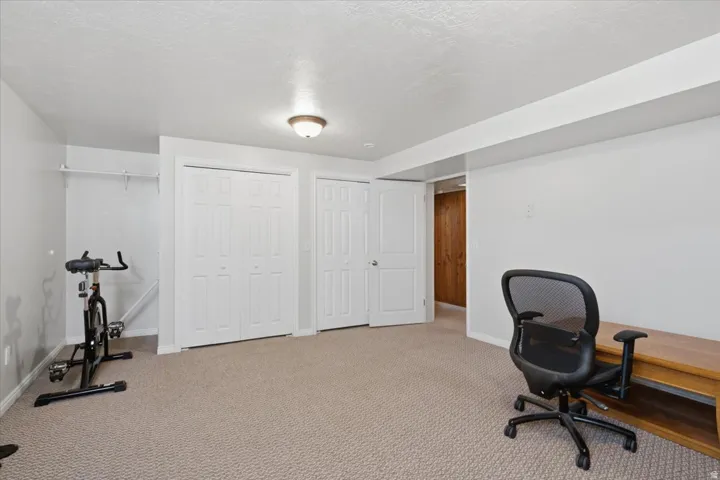 Carpeted room featuring multiple bi-fold doors, a single panel door, and a flush mount ceiling light