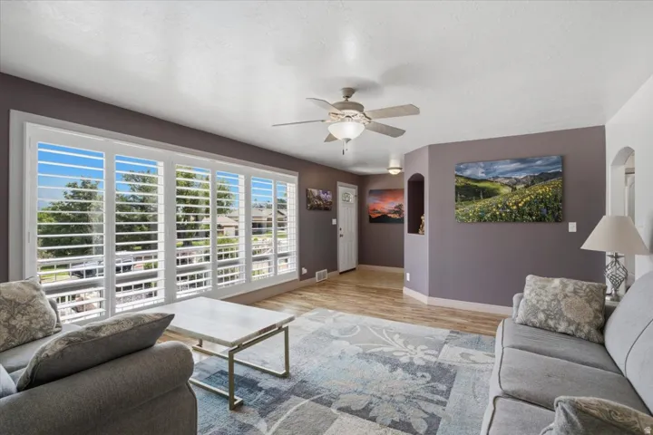 Spacious living area featuring large windows with plantation shutters, wood-finish flooring, and arched wall niches
