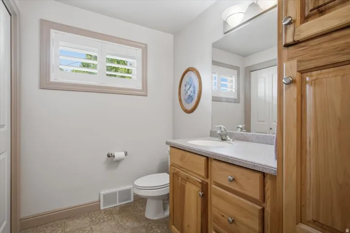 Bathroom featuring a wood-finish vanity with an integrated sink, a large mirror, and wall-mounted lighting