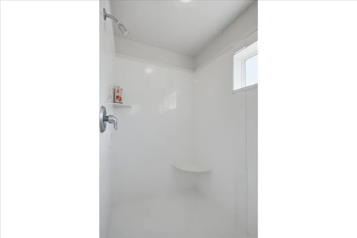 Walk-in shower with a built-in bench, integrated shelving, and a brushed nickel shower head