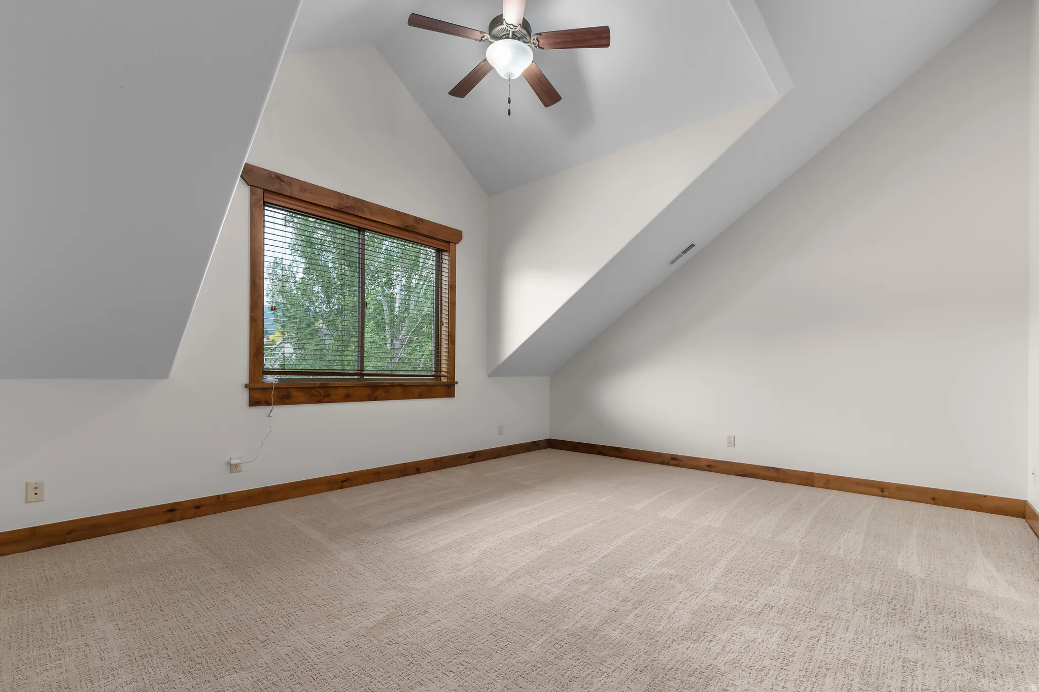 White walls with sloped ceilings and a ceiling fan