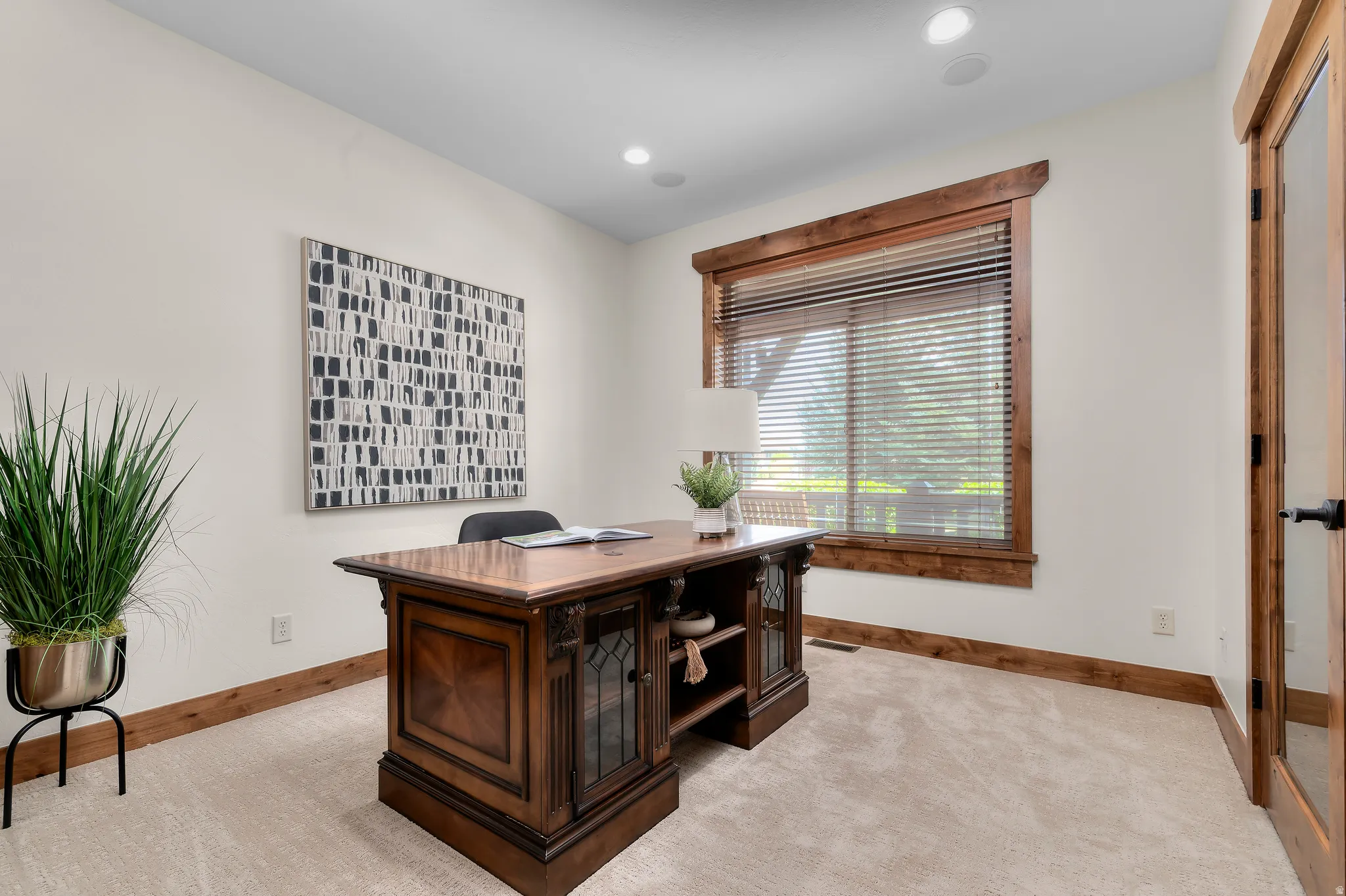 Plush carpet flooring, recessed ceiling lighting, wood-trimmed window, wood baseboards, and a wood-trimmed glass panel door