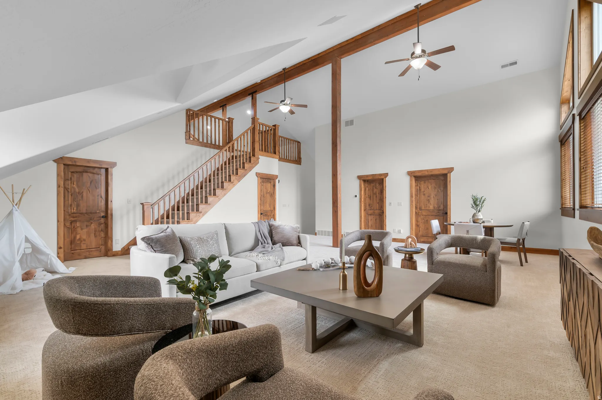 Vaulted ceilings with exposed wood beams, wood-finish doors and trim, and an expansive open-concept layout