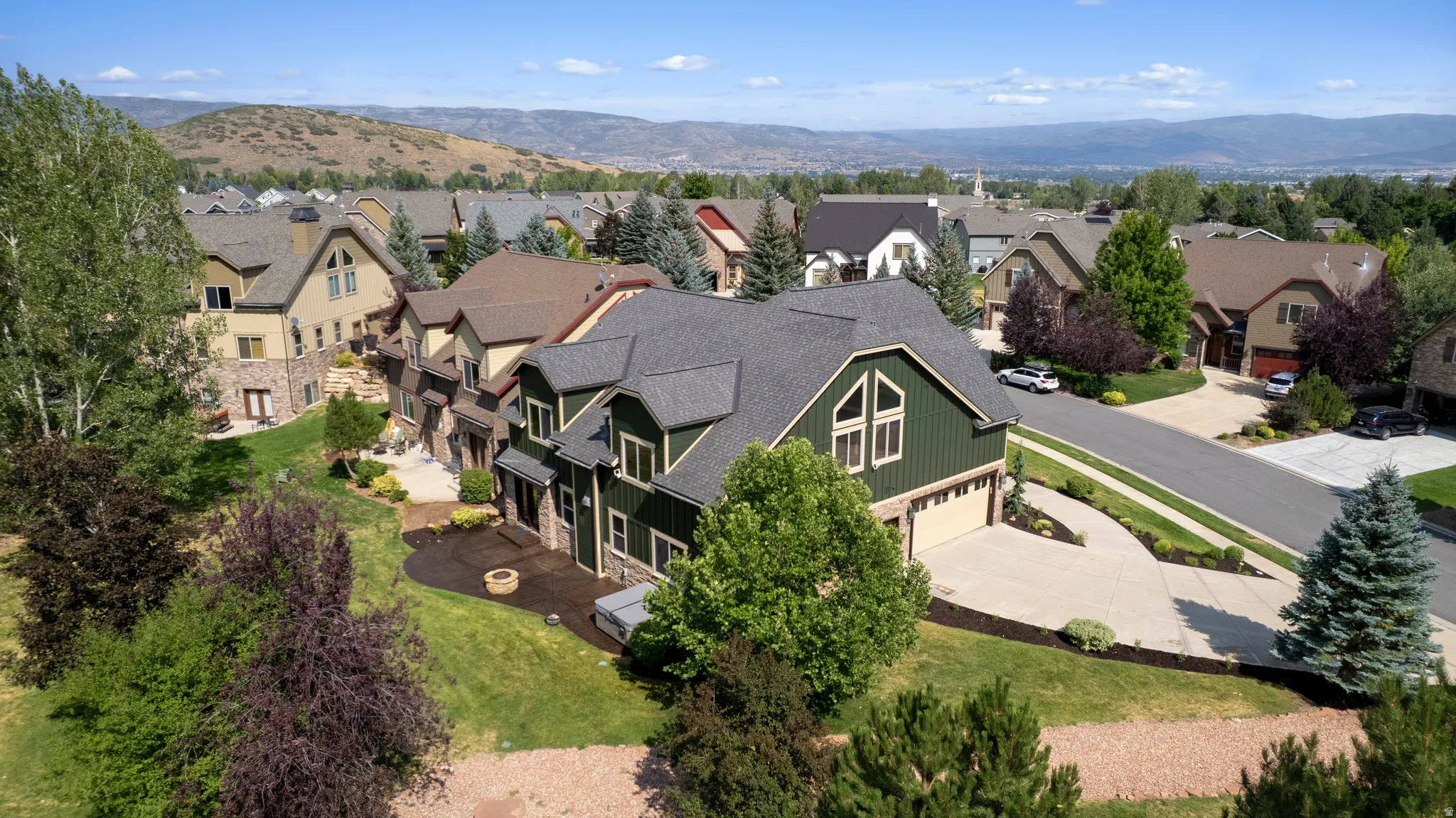 Contemporary-style residence featuring a dark green exterior, attached garage, and a paved driveway
