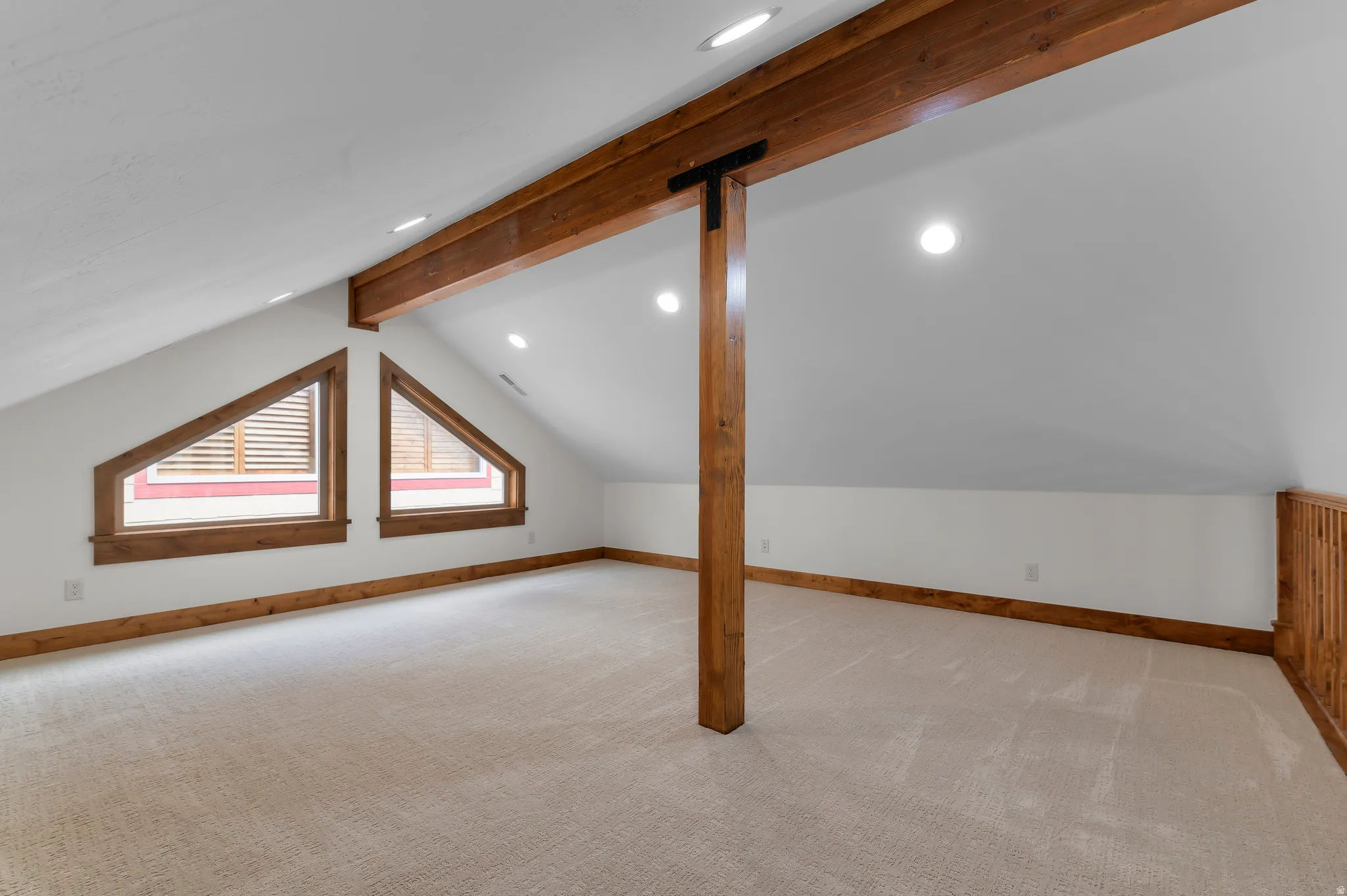 Angled windows with wood trim, wood beam accents, recessed lighting, and carpet flooring