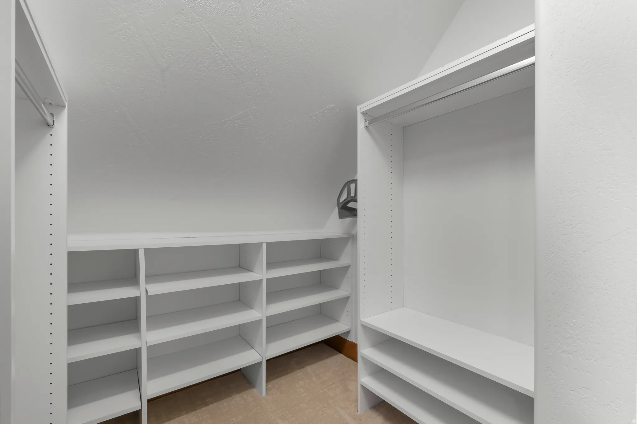 Built-in closet shelving, integrated hanging rods, and carpeted flooring