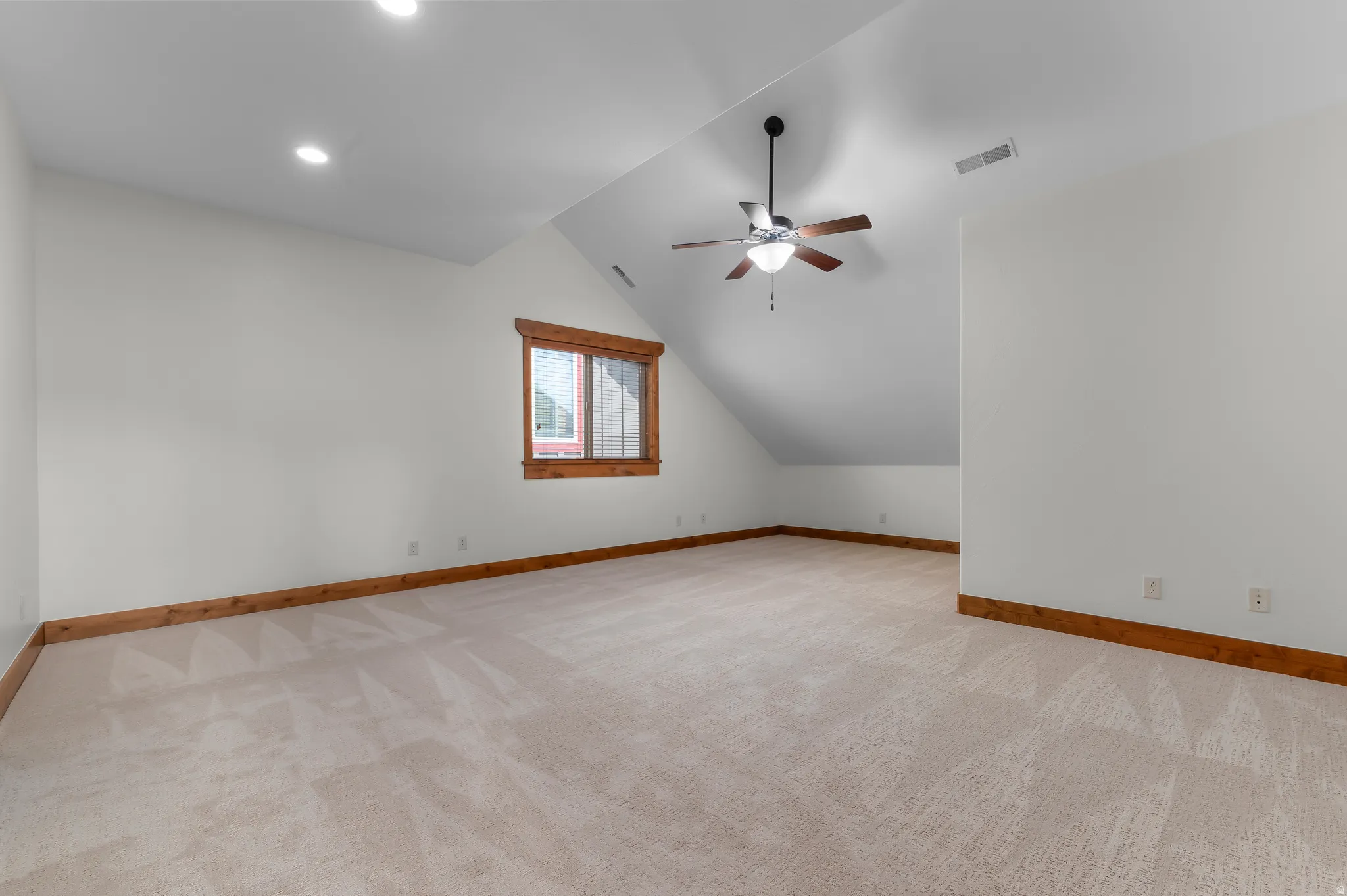 Carpeted room featuring a sloped ceiling, recessed lighting, and a ceiling fan with integrated light