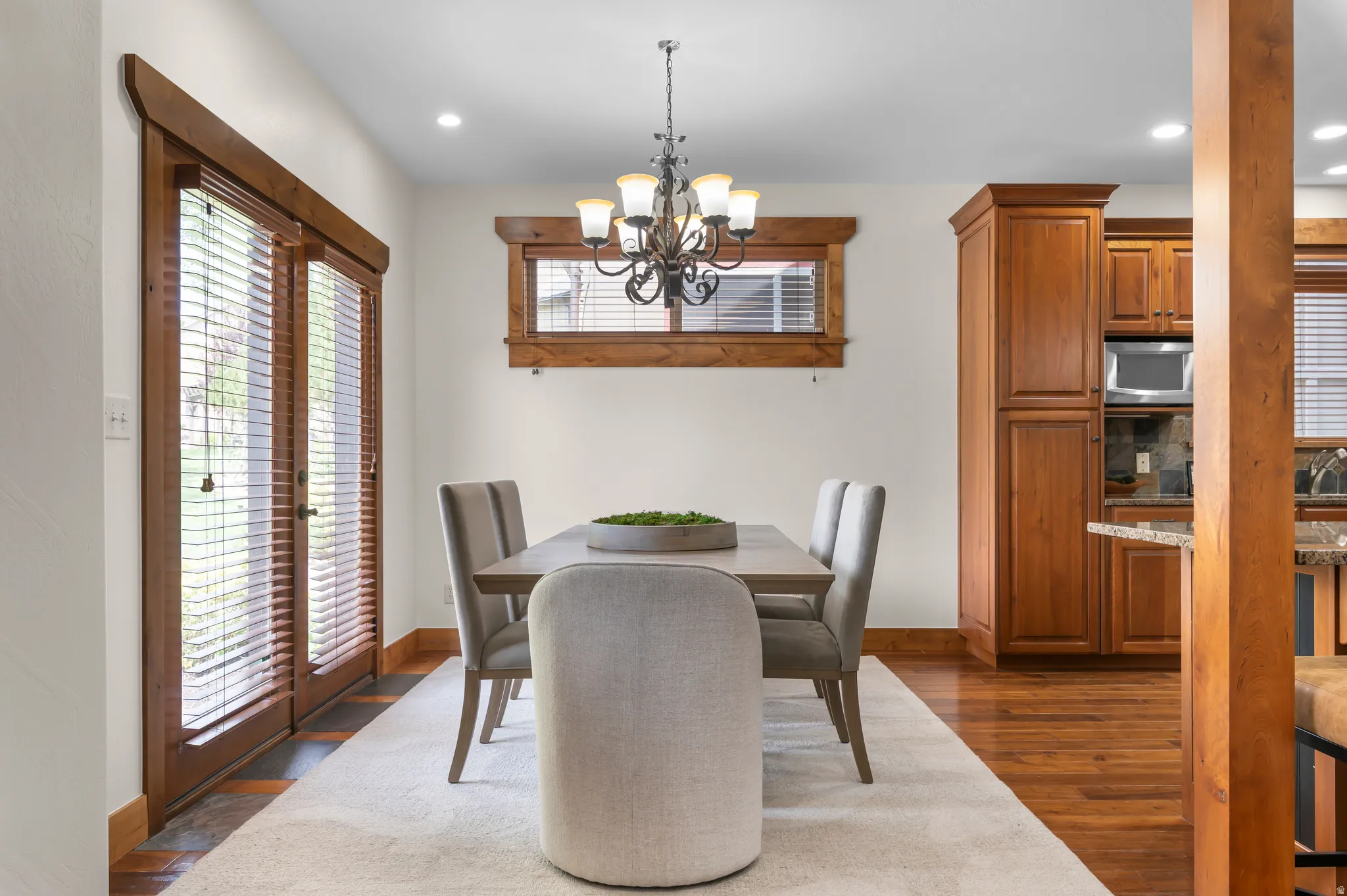 Dining area with wood-finish flooring, a wrought iron chandelier, and direct outdoor access through wood-framed French doors